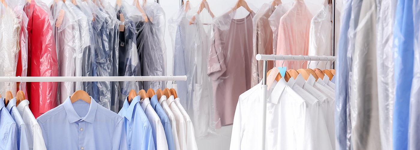 Racks with clean clothes on hangers after dry-cleaning indoors